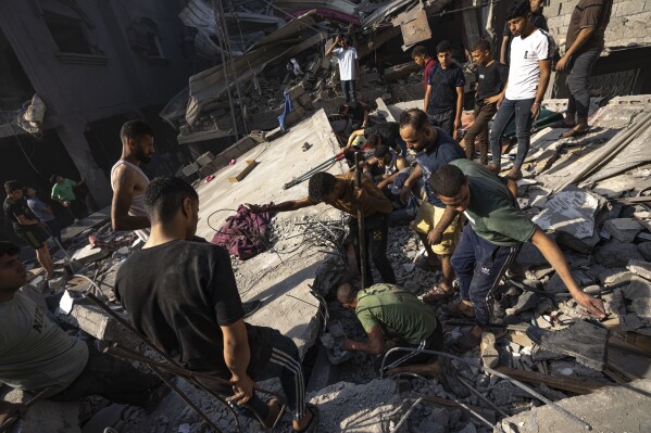 Palestinians search for bodies and survivors in the rubble of a residential building leveled in an Israeli airstrike, in Al Shati refugee camp Thursday, Oct. 12, 2023. (AP Photo/Fatima Shbair)