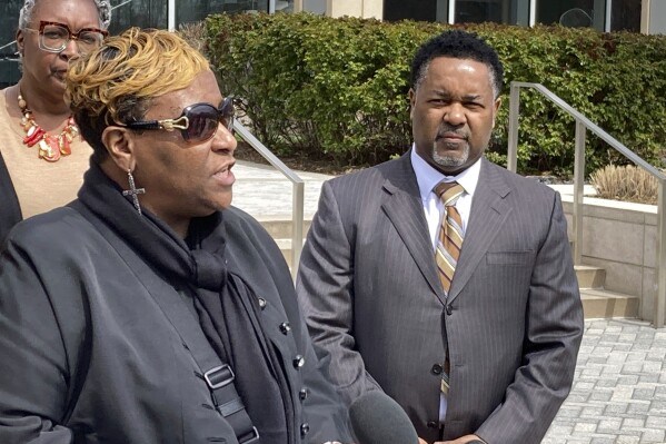 FILE - Timothy McCree Johnson's mother, Melissa Johnson, along with attorney, Carl Crews, addresses reporters outside Fairfax County Police Department headquarters, March 22, 2023, in Fairfax, Va., after viewing police body camera video of her son's shooting death at the hands of police in February outside Tysons Corner Center shopping mall. A special grand jury in Virginia on Thursday, Oct. 12, indicted a former police officer for involuntary manslaughter in the fatal shooting of Timothy McCree Johnson, an unarmed shoplifting suspect outside the Virginia shopping mall. (AP Photo/Matthew Barakat, File)