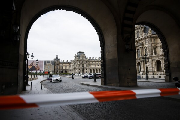Police officers stand guard outside the Louvre Museum as people are evacuated after it received a written threat, in Paris, Saturday Oct. 14, 2023. The Louvre Museum says it is closing for the day and evacuating all visitors and staff after a threat. (AP Photo/Thomas Padilla)