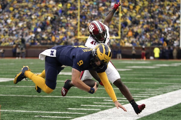 Michigan quarterback J.J. McCarthy (9) is knocked out of bounds by Indiana linebacker Lanell Carr Jr. (41) in the first half of an NCAA college football game in Ann Arbor, Mich., Saturday, Oct. 14, 2023. (AP Photo/Paul Sancya)