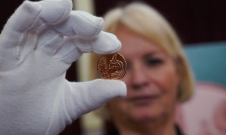 woman with gloved hand holding up new 2p coin with red squirrel