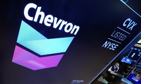 The logo for Chevron appears above a trading post on the floor of the New York Stock Exchange