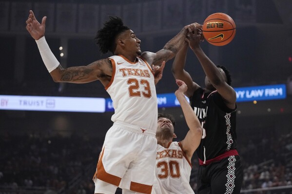 Texas forward Dillon Mitchell (23) and forward Brock Cunningham (30) defend Incarnate Word center Josh Akpovwa during the first half of an NCAA college basketball game, Monday, Nov. 6, 2023, in Austin, Texas. (AP Photo/Eric Gay)