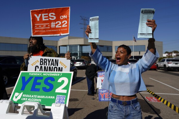 Nikko Griffin, left, and Tyra Patterson, call out to arriving voters in the parking lot of the Hamilton County Board of Elections during early in-person voting in Cincinnati, Thursday, Nov. 2, 2023. They urge people to vote for different issues, including Issue 2, which would allow adult-use sale, purchase, and possession of cannabis for Ohioans who are 21 and older. They also pass out Hamilton County Democratic Party sample ballots. Ohioans will decide Nov. 7, on whether to legalize recreational marijuana, but people on both sides of the issue say more hangs in the balance than simply decriminalizing the drug. (AP Photo/Carolyn Kaster)