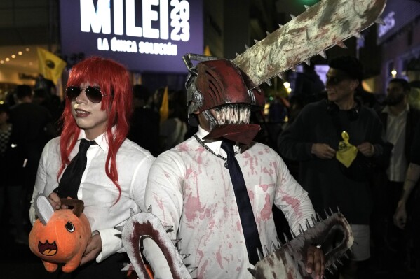 Supporters of presidential hopeful Javier Milei wear chainsaw costumes outside his campaign headquarters after polls closed for general elections in Buenos Aires, Argentina, Sunday, Oct. 22, 2023. The chainsaw is a prop that Milei often holds up at rallies to symbolize what he wants to do with state spending. A presidential runoff election is set for Nov. 19. (AP Photo/Rodrigo Abd)